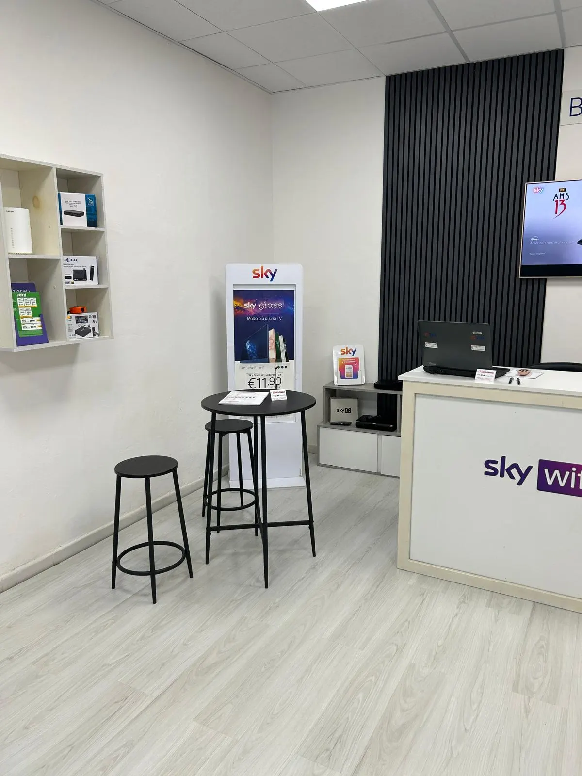 Angolo Sky con Sky Glass e due sgabelli al tavolo per parlare delle offerte
